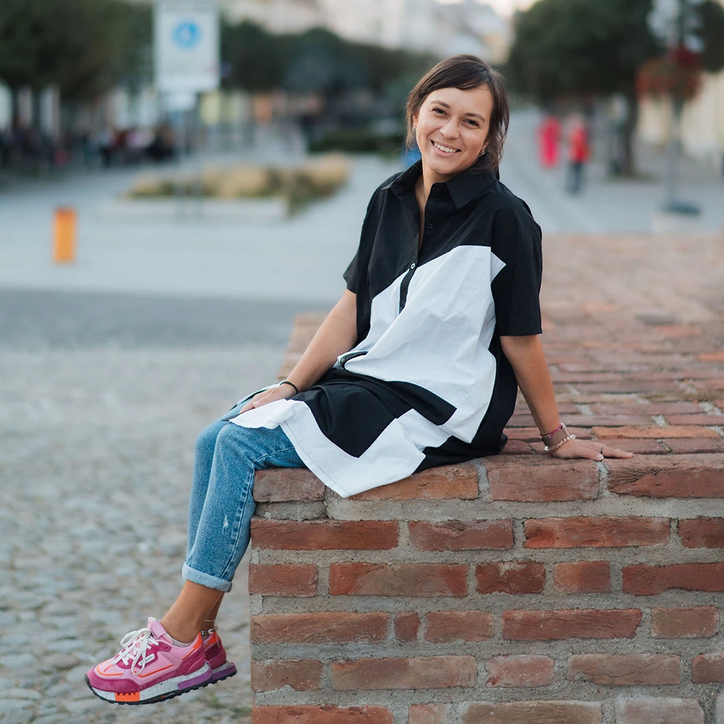 Usmiata Kamila sedí na tehlovom múriku v exteriéri