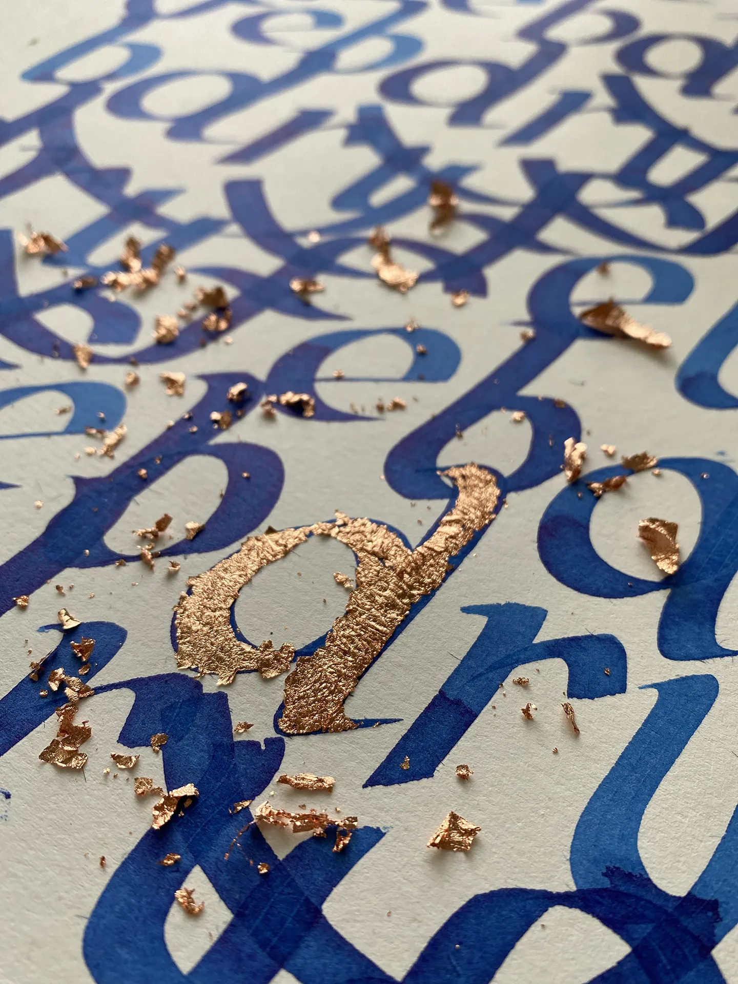 Detail hustého modrého letteringu s rozmiestnenými medenými lístkami