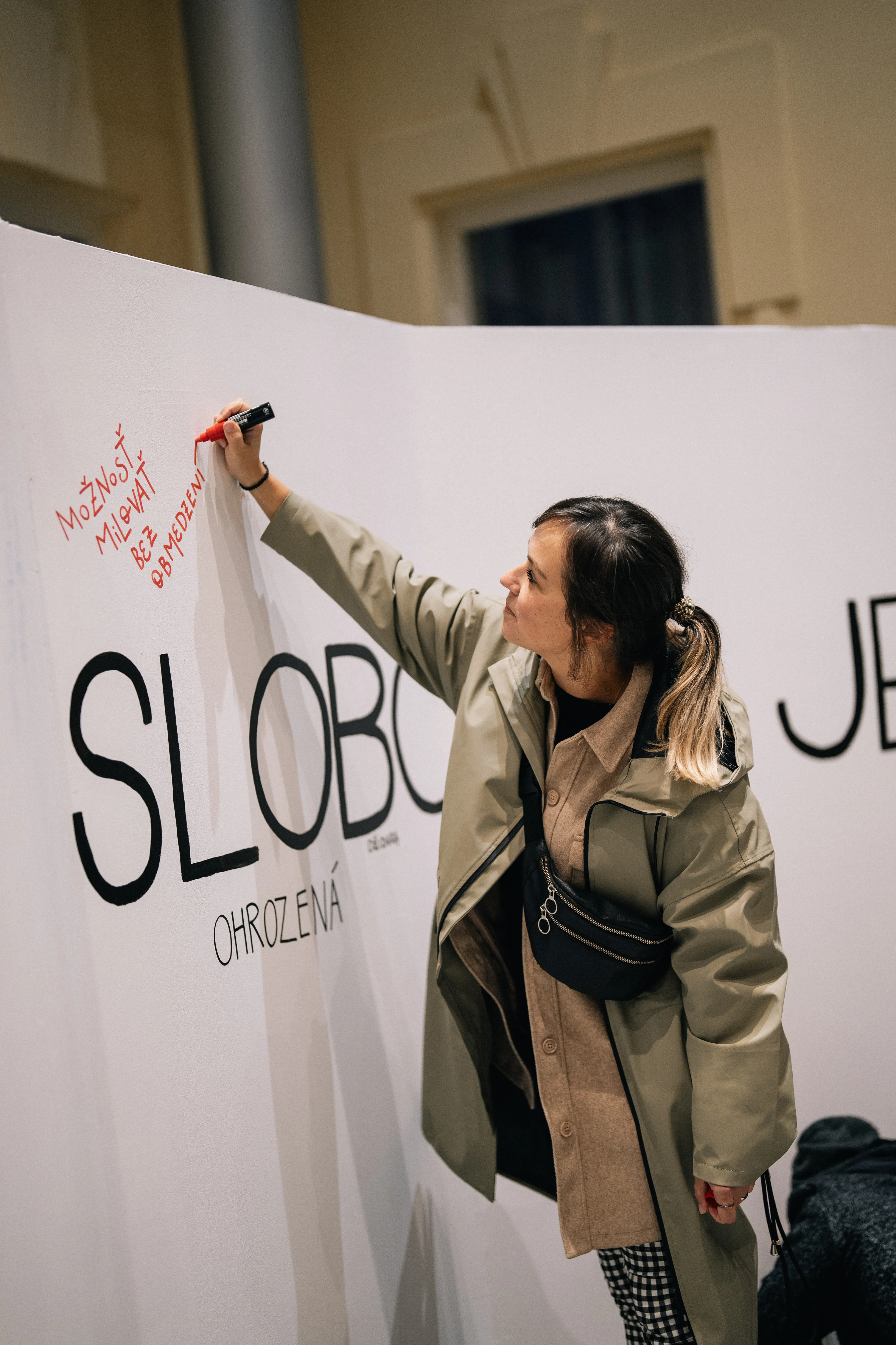 Kamila píše veľký nápis „SLOBODA…“ na stenu